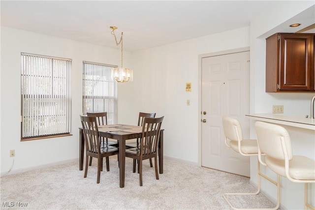 dining area with light carpet, baseboards, and a chandelier