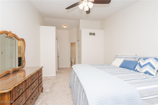 bedroom with light carpet, baseboards, visible vents, a ceiling fan, and ensuite bath