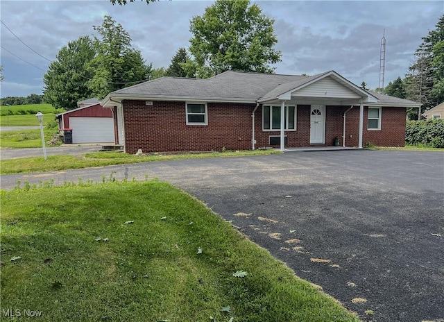 ranch-style home featuring brick siding, a detached garage, and driveway