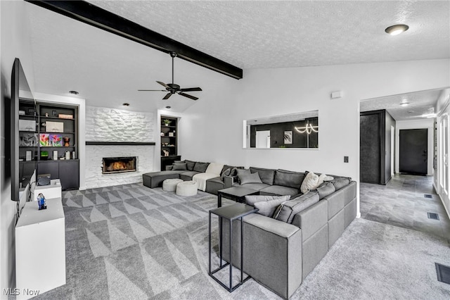 living room featuring lofted ceiling with beams, a textured ceiling, a stone fireplace, carpet flooring, and visible vents