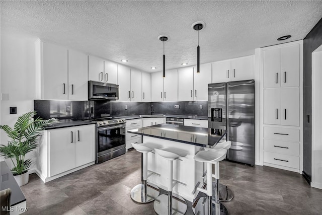 kitchen with stainless steel appliances, dark countertops, white cabinetry, and decorative backsplash