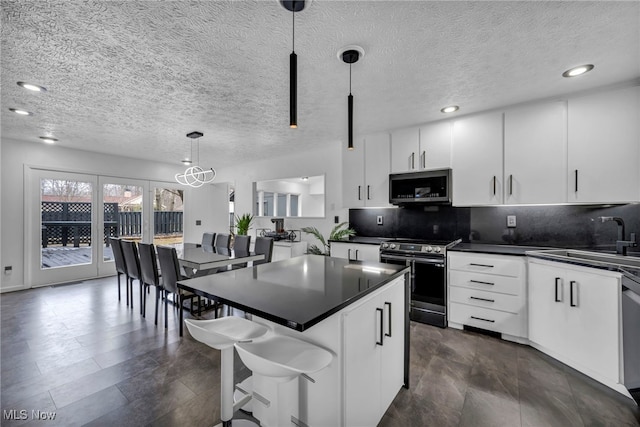 kitchen with pendant lighting, dark countertops, decorative backsplash, appliances with stainless steel finishes, and a sink