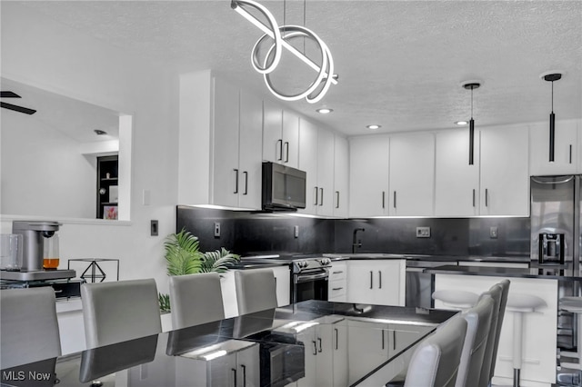 kitchen featuring tasteful backsplash, dark countertops, appliances with stainless steel finishes, a textured ceiling, and white cabinetry