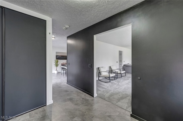 hall featuring baseboards and a textured ceiling