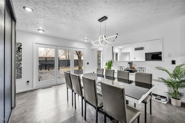 dining area featuring visible vents, a textured ceiling, and an inviting chandelier