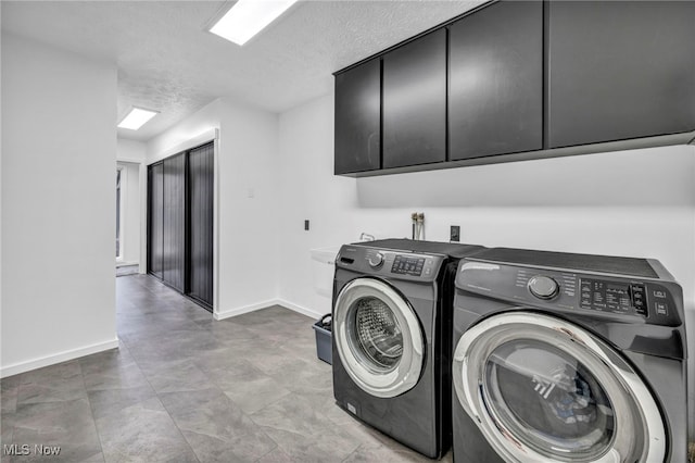 washroom with cabinet space, baseboards, separate washer and dryer, and a textured ceiling