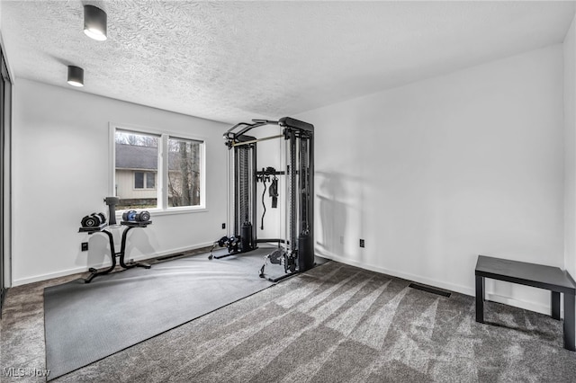 workout room featuring a textured ceiling, carpet flooring, visible vents, and baseboards