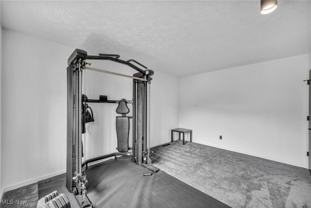 exercise area featuring carpet, a textured ceiling, and baseboards