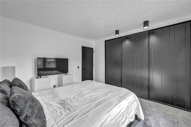 carpeted bedroom with a textured ceiling and a closet