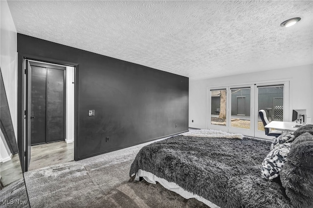 bedroom featuring access to exterior, baseboards, and a textured ceiling