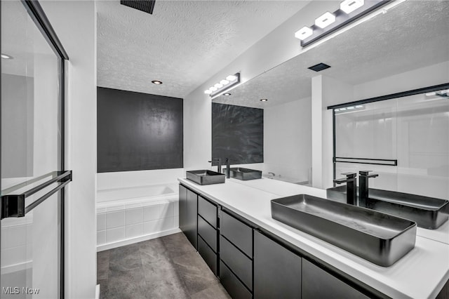 full bathroom with a garden tub, double vanity, visible vents, a sink, and a textured ceiling