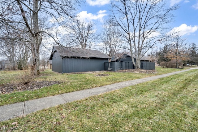 view of property exterior with fence, a lawn, and an outdoor structure