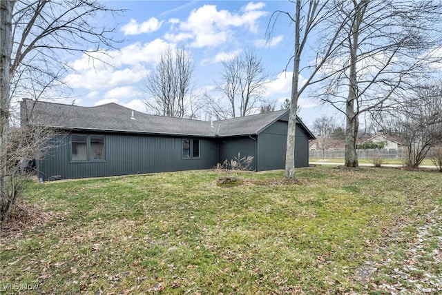 back of house featuring a lawn and fence