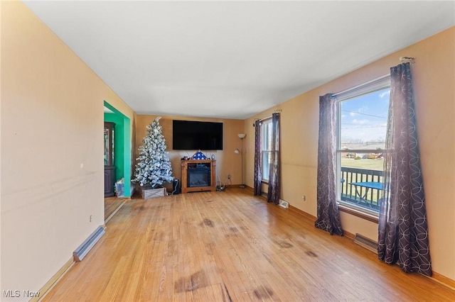 unfurnished living room featuring hardwood / wood-style flooring, visible vents, a fireplace, and baseboards