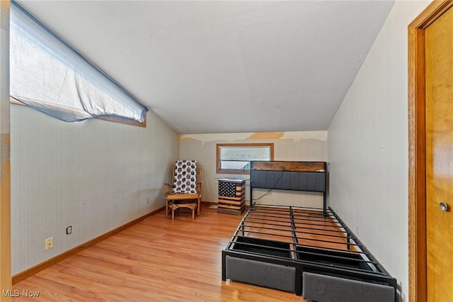 bedroom with vaulted ceiling, baseboards, and wood finished floors