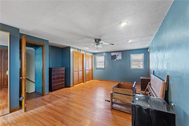 living area with a ceiling fan, a textured ceiling, baseboards, and wood finished floors