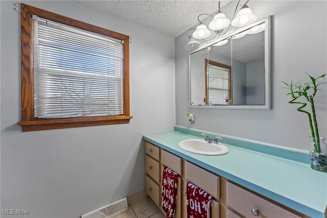 bathroom with visible vents, a textured ceiling, vanity, and tile patterned floors