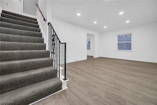 below grade area with stairs, baseboards, wood finished floors, and recessed lighting