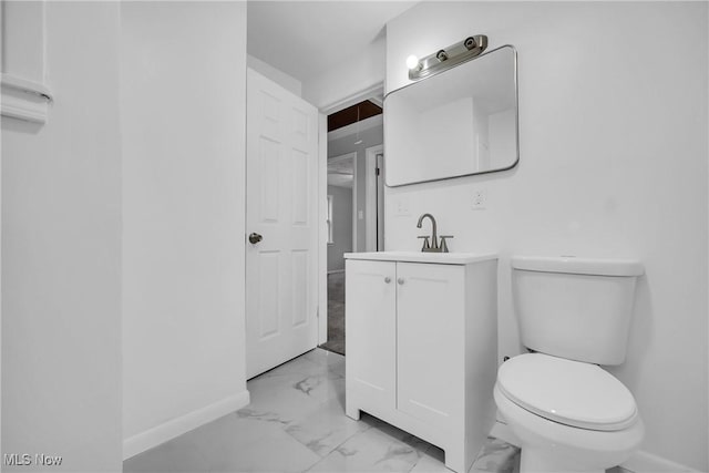 bathroom with marble finish floor, baseboards, vanity, and toilet