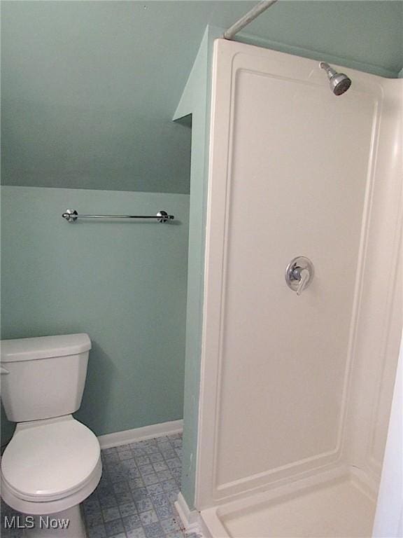 full bath with a stall shower, toilet, vaulted ceiling, and baseboards