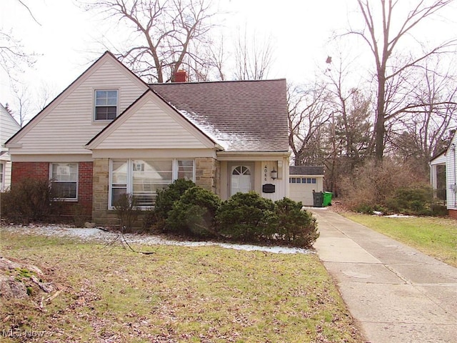 bungalow-style house featuring a shingled roof, brick siding, stone siding, a chimney, and a front yard