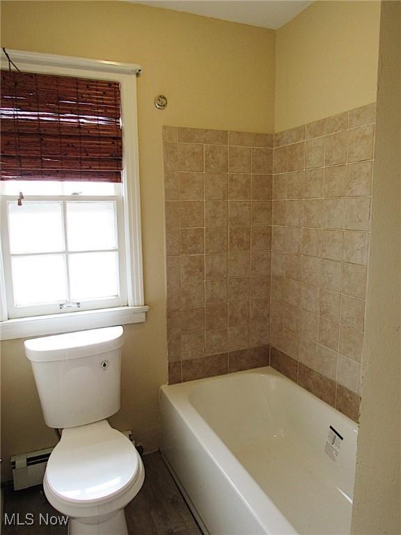 bathroom with toilet, a tub, a baseboard heating unit, and wood finished floors