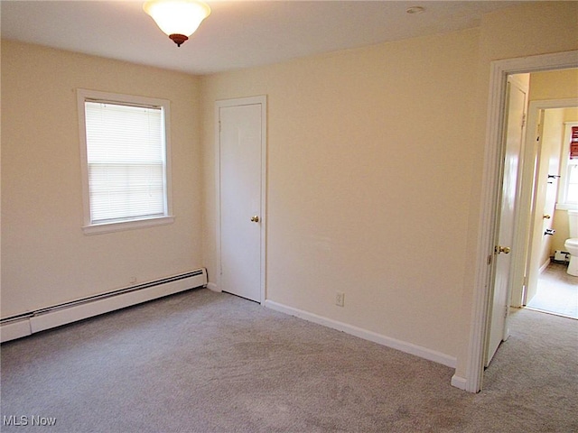 empty room with light carpet, a baseboard radiator, and baseboards