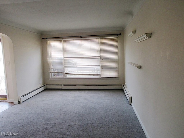 carpeted spare room featuring baseboards and arched walkways