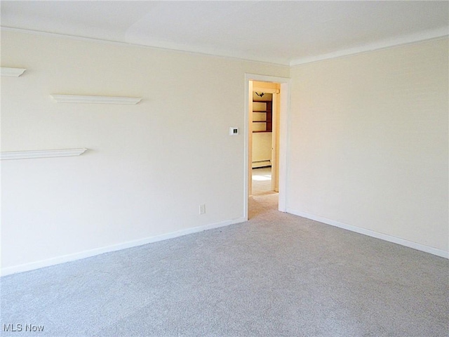 carpeted empty room featuring a baseboard heating unit, baseboards, and crown molding