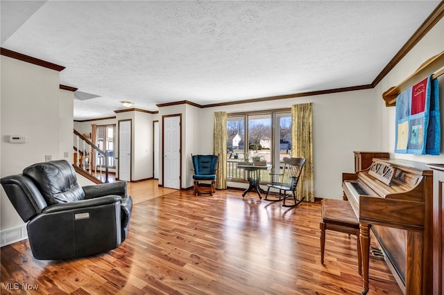 living room with visible vents, stairway, ornamental molding, a textured ceiling, and wood finished floors