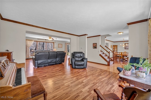 living area with ornamental molding, light wood finished floors, a textured ceiling, and stairs