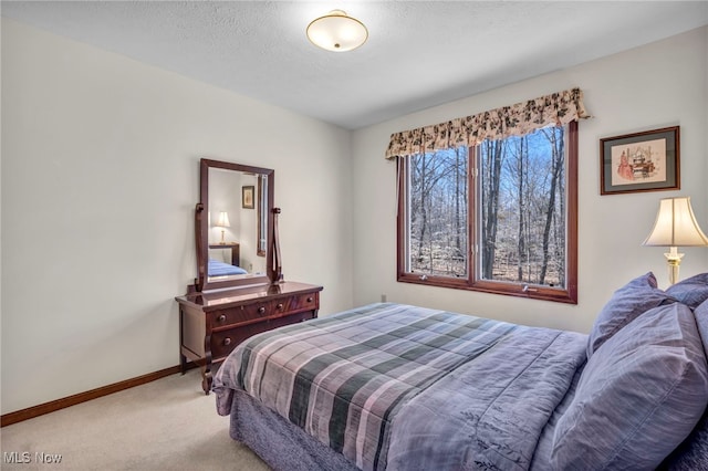 bedroom featuring light carpet, a textured ceiling, and baseboards