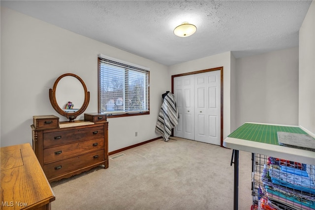 bedroom with light carpet, baseboards, visible vents, a textured ceiling, and a closet