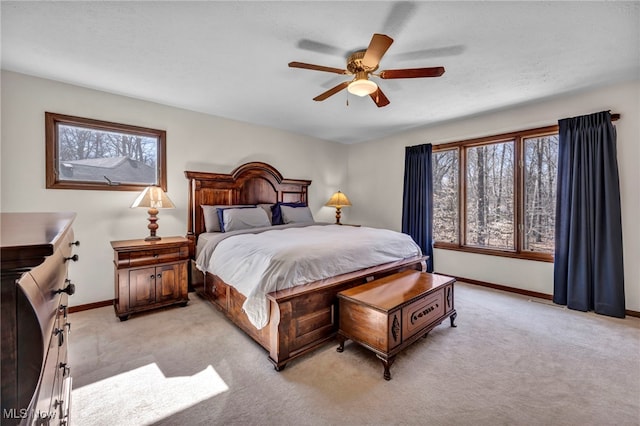 bedroom with a ceiling fan, light colored carpet, baseboards, and multiple windows