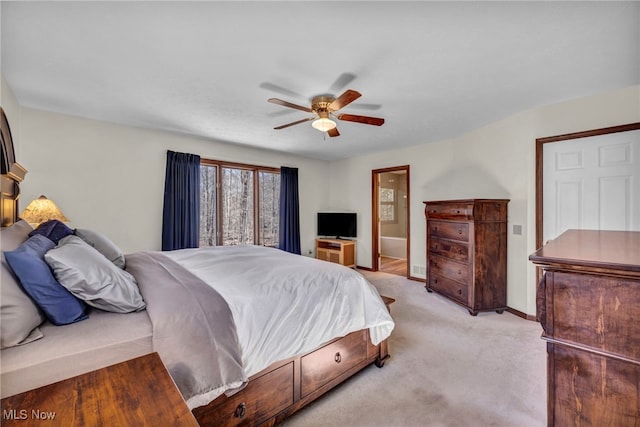 bedroom featuring light carpet, ensuite bathroom, a ceiling fan, and baseboards