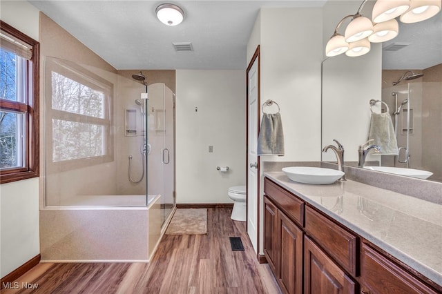 bathroom featuring a stall shower, visible vents, toilet, and wood finished floors