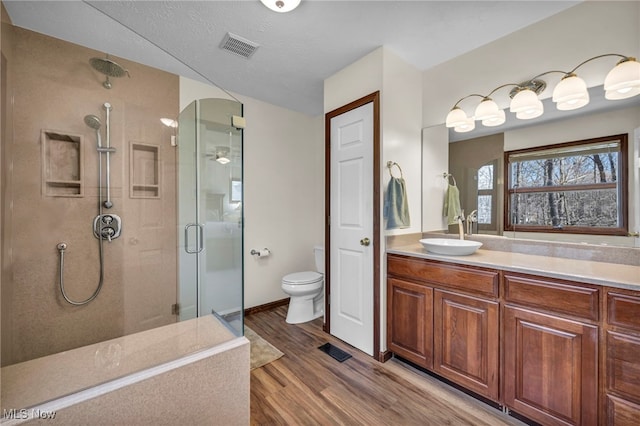 full bath featuring visible vents, toilet, a stall shower, vanity, and wood finished floors