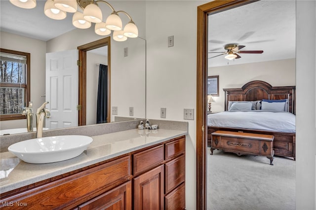 ensuite bathroom featuring a sink, double vanity, ceiling fan with notable chandelier, and ensuite bath