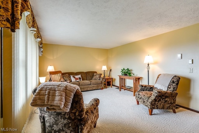 living area with a textured ceiling, baseboards, and carpet flooring