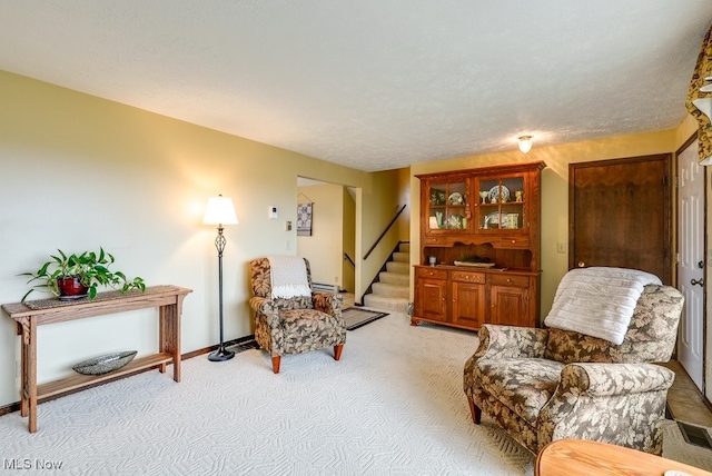 living area featuring light colored carpet, stairway, and baseboards