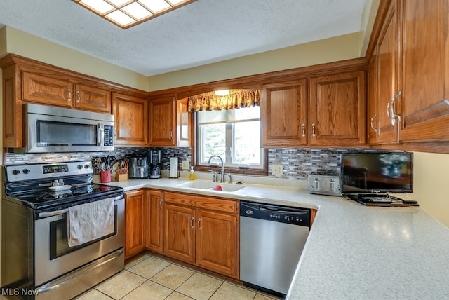 kitchen with stainless steel appliances, a sink, light countertops, backsplash, and brown cabinets