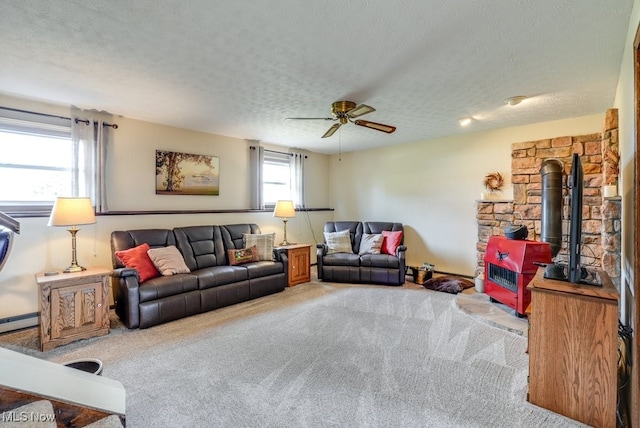 living room with carpet floors, a wood stove, a textured ceiling, and a ceiling fan