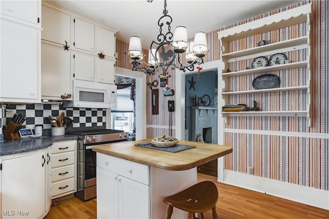 1518 Washington Ave, Parkersburg, WV 26101 - kitchen featuring stainless steel range with gas cooktop, open shelves, white microwave, white cabinetry, and butcher block countertops