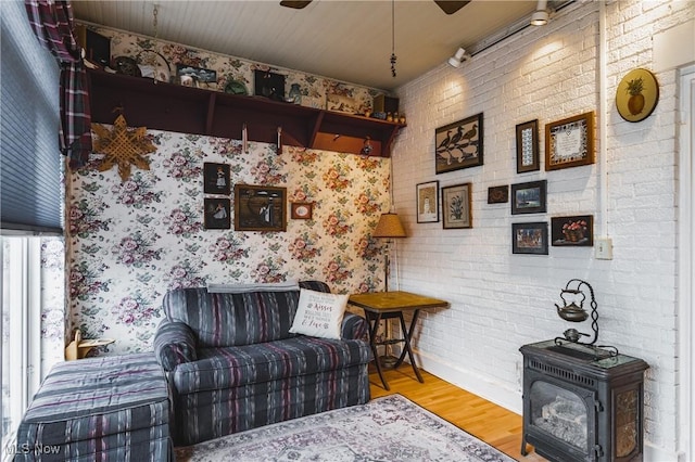 1518 Washington Ave, Parkersburg, WV 26101 - living area featuring a ceiling fan, a wood stove, brick wall, and wood finished floors