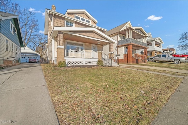 view of front of property with a porch, a detached garage, and a front lawn