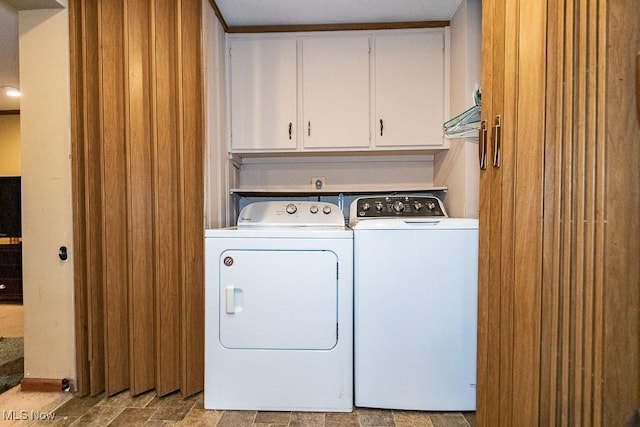 washroom with cabinet space, washing machine and dryer, and stone finish floor