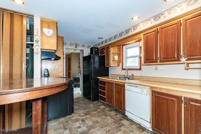 kitchen with freestanding refrigerator, stone finish flooring, white dishwasher, light countertops, and a sink