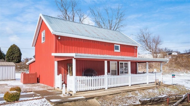 view of front of home featuring fence, metal roof, and an outbuilding