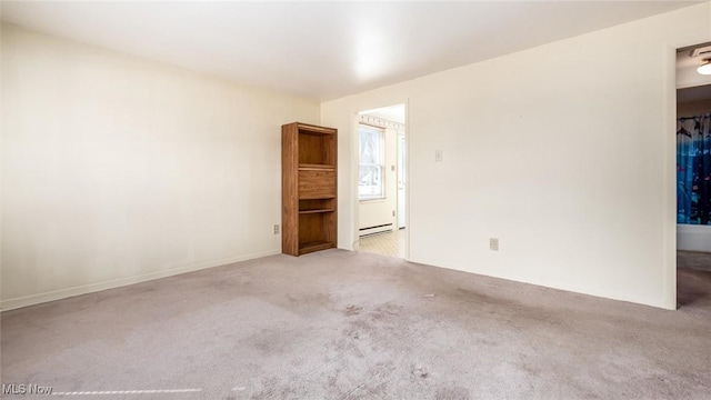 carpeted empty room with a baseboard heating unit
