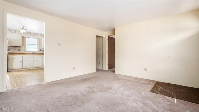 unfurnished room featuring light colored carpet, ceiling fan, and a sink